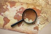 Magnifying glass on vintage world map with parchment texture