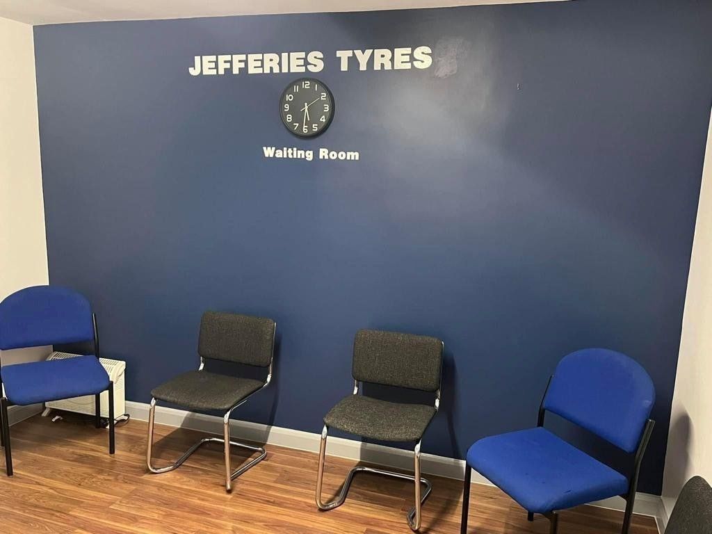 A waiting room for jefferies tyres with blue chairs and a clock on the wall