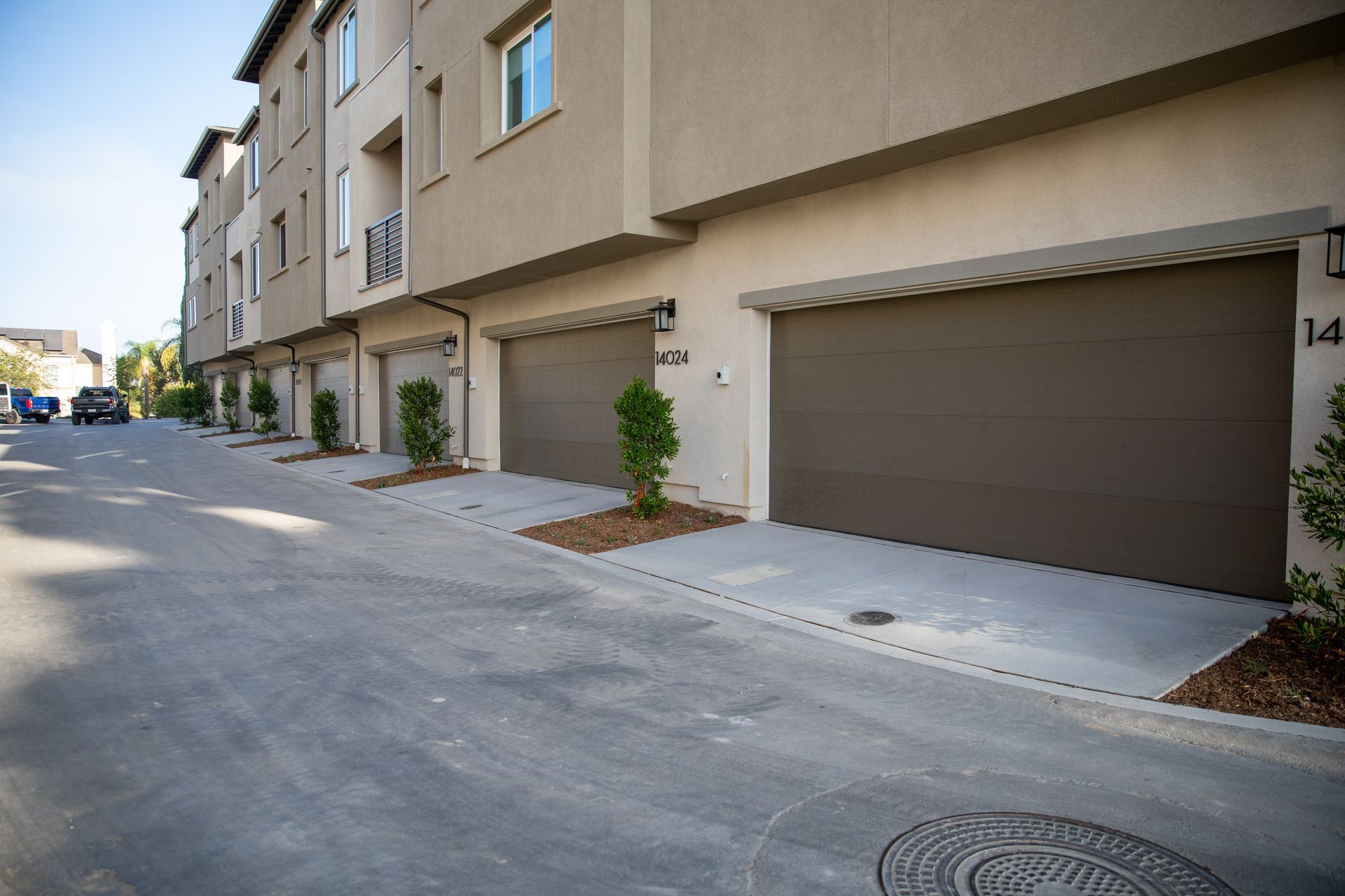 Row of townhomes with garage doors and a paved driveway.