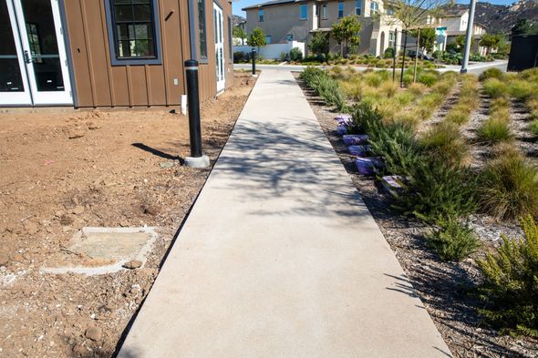 A concrete walkway leading to a house in a residential area