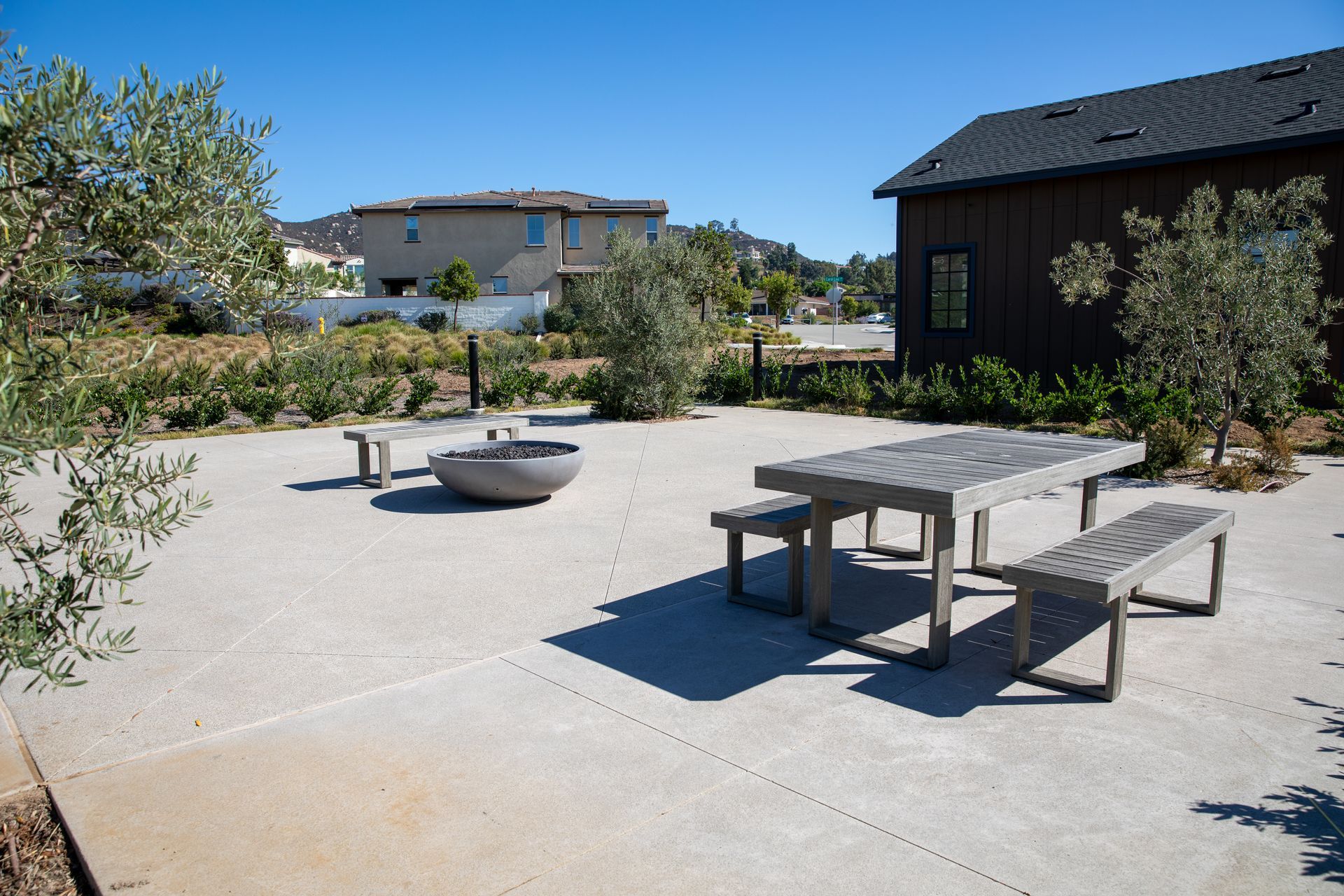 A picnic table with benches and a fire pit in front of a house.