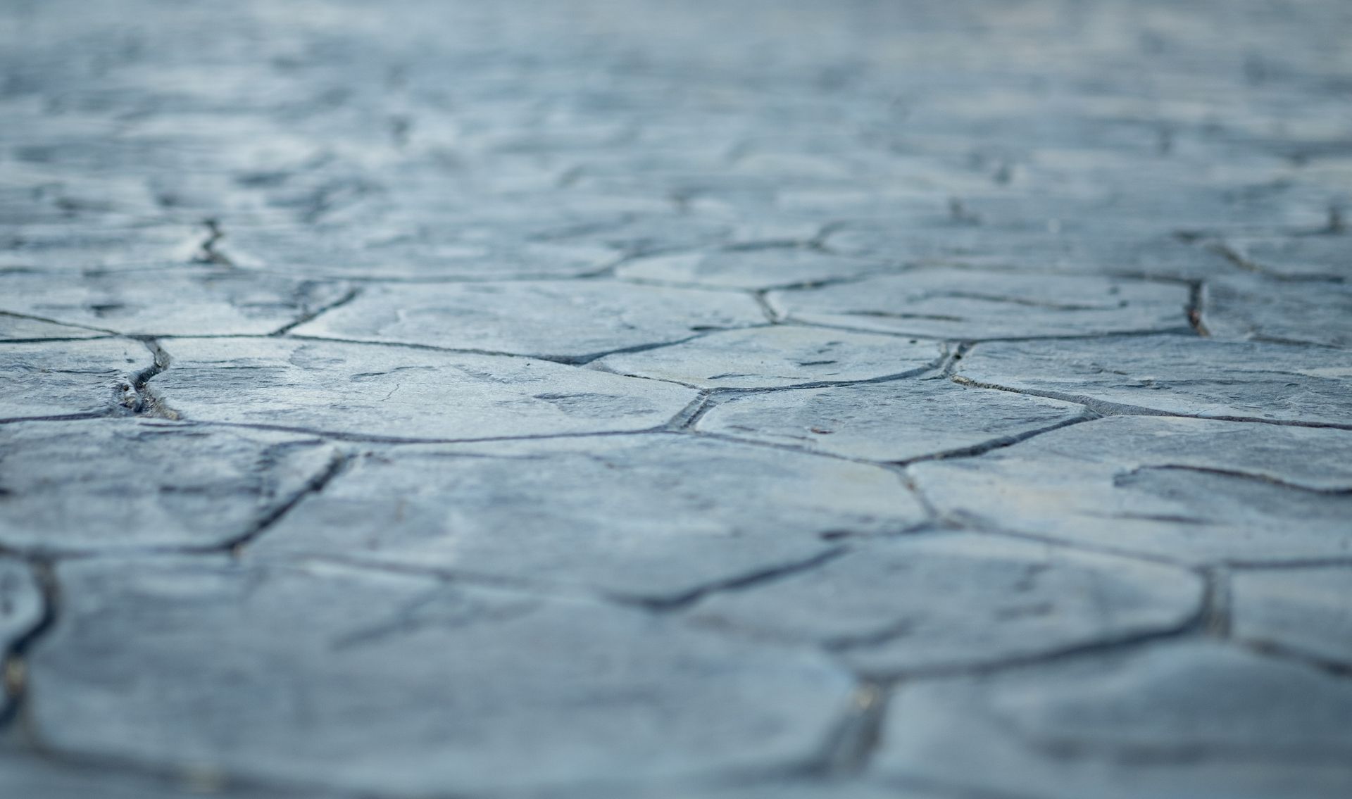Cracked light gray dry ground with a rough, textured surface