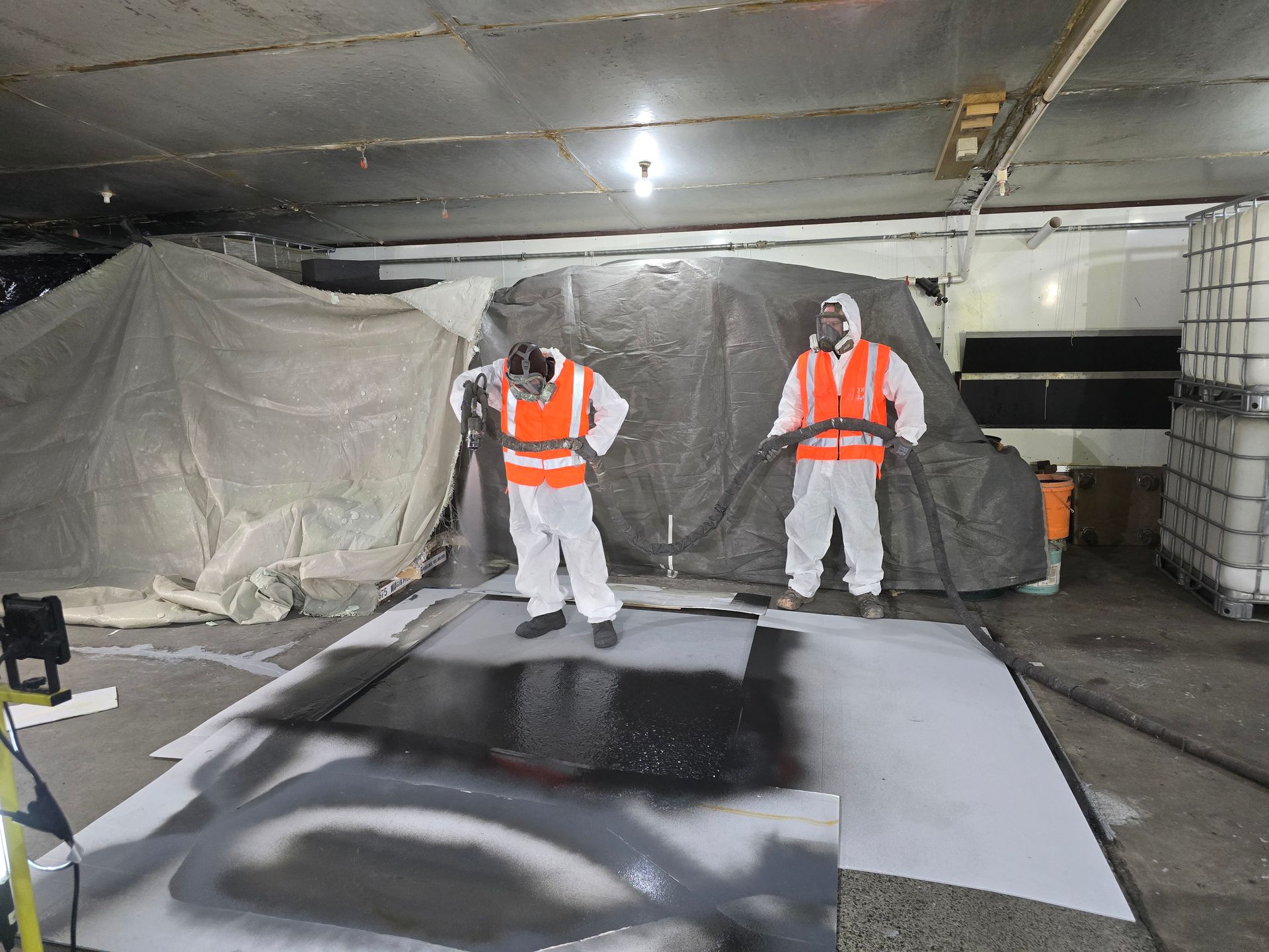 Two men are standing in a room with a tarp on the ceiling.