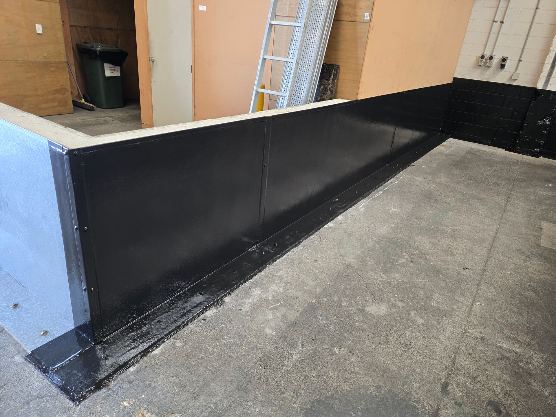 A black wall is sitting on a concrete floor in a room.