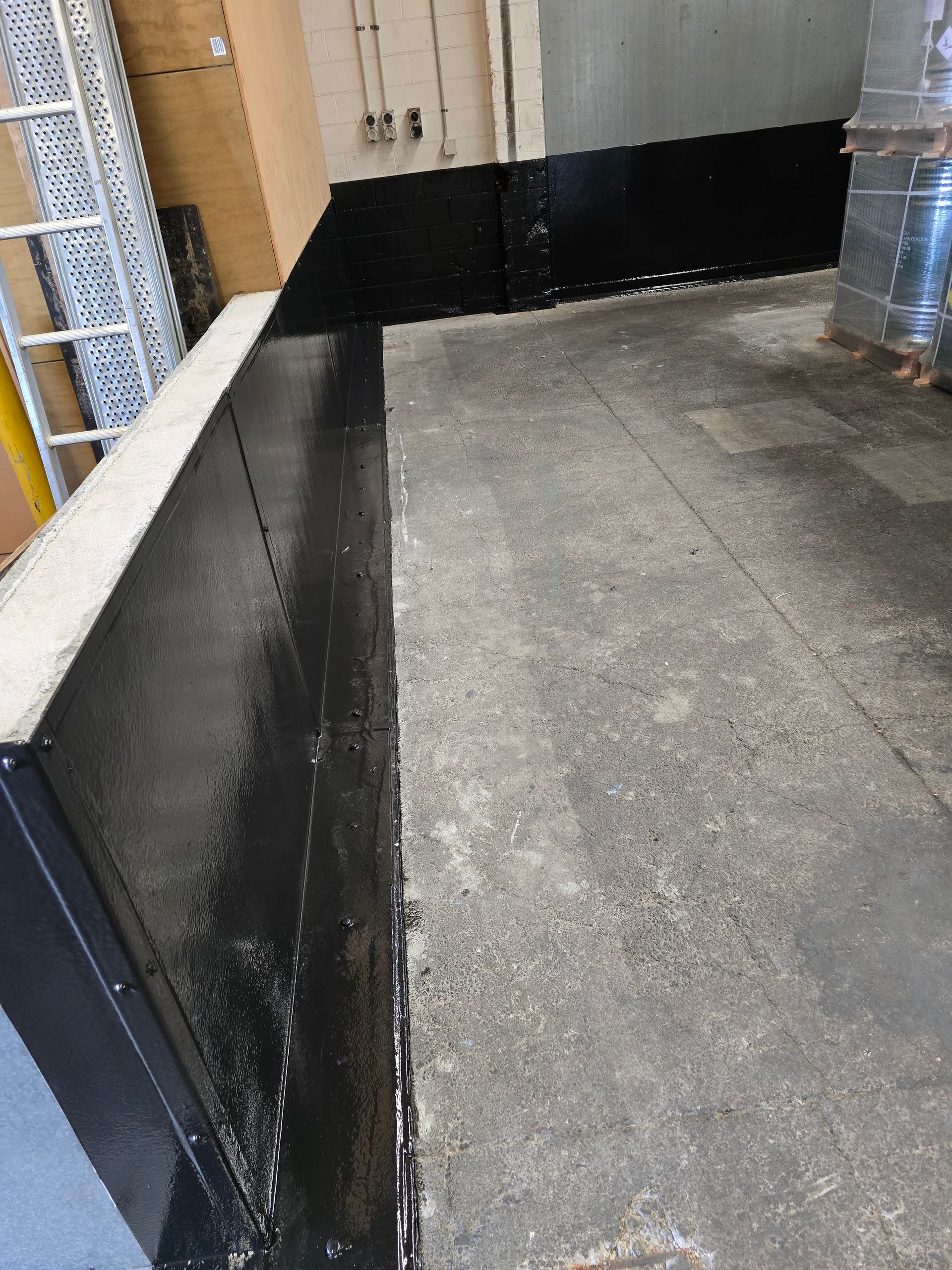 A black wall is sitting on a concrete floor in a warehouse.