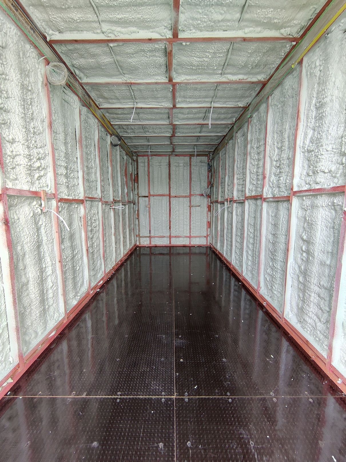 An empty room with a black floor and walls covered in foam.