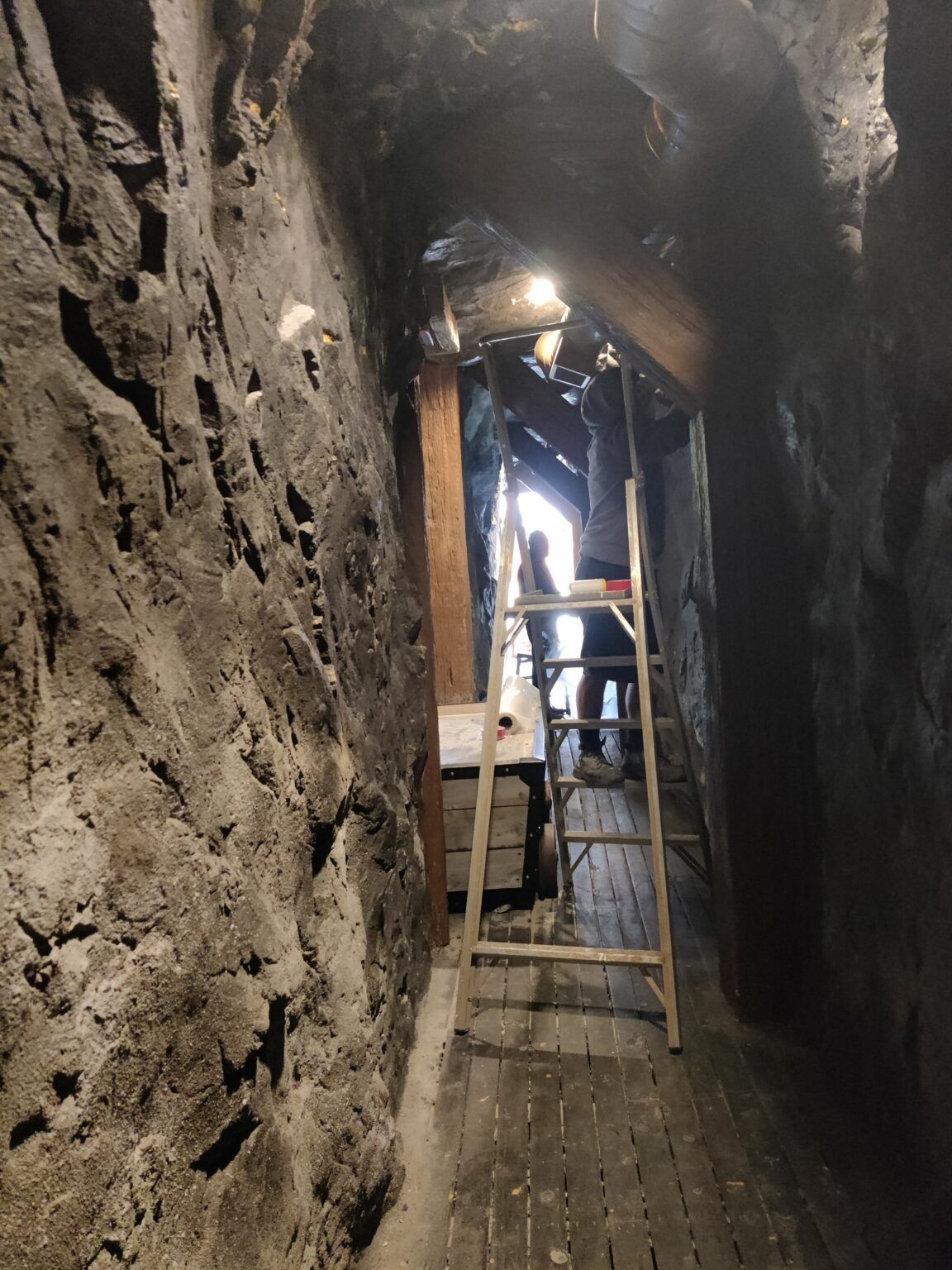 A ladder is hanging from the ceiling of a cave.