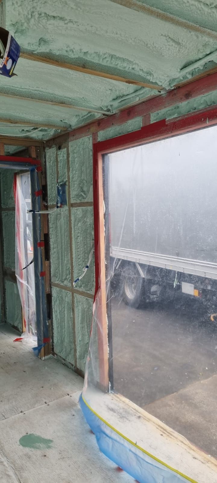 A room with a large window and a truck in the background.