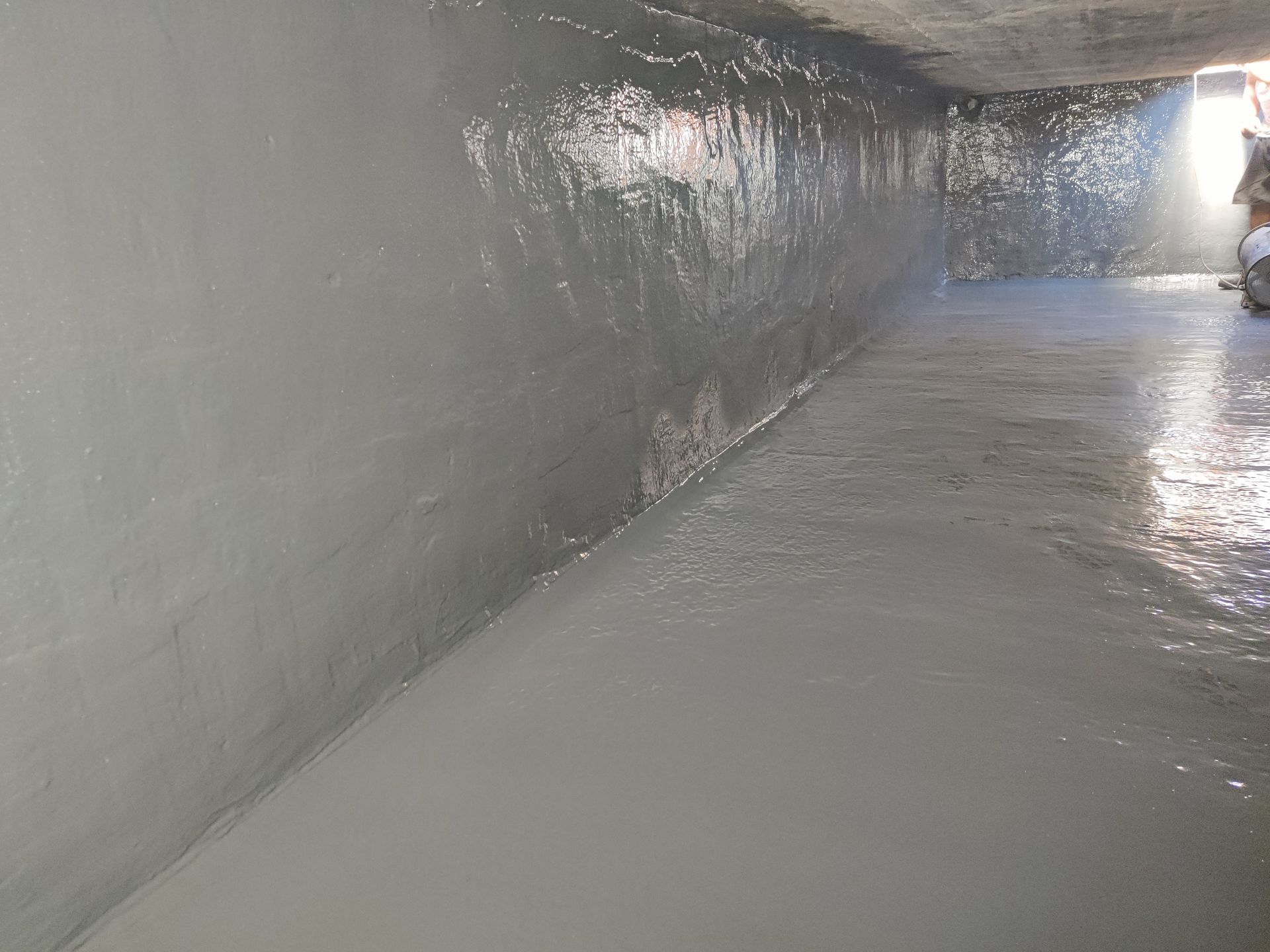 A man is painting a wall in a tunnel.