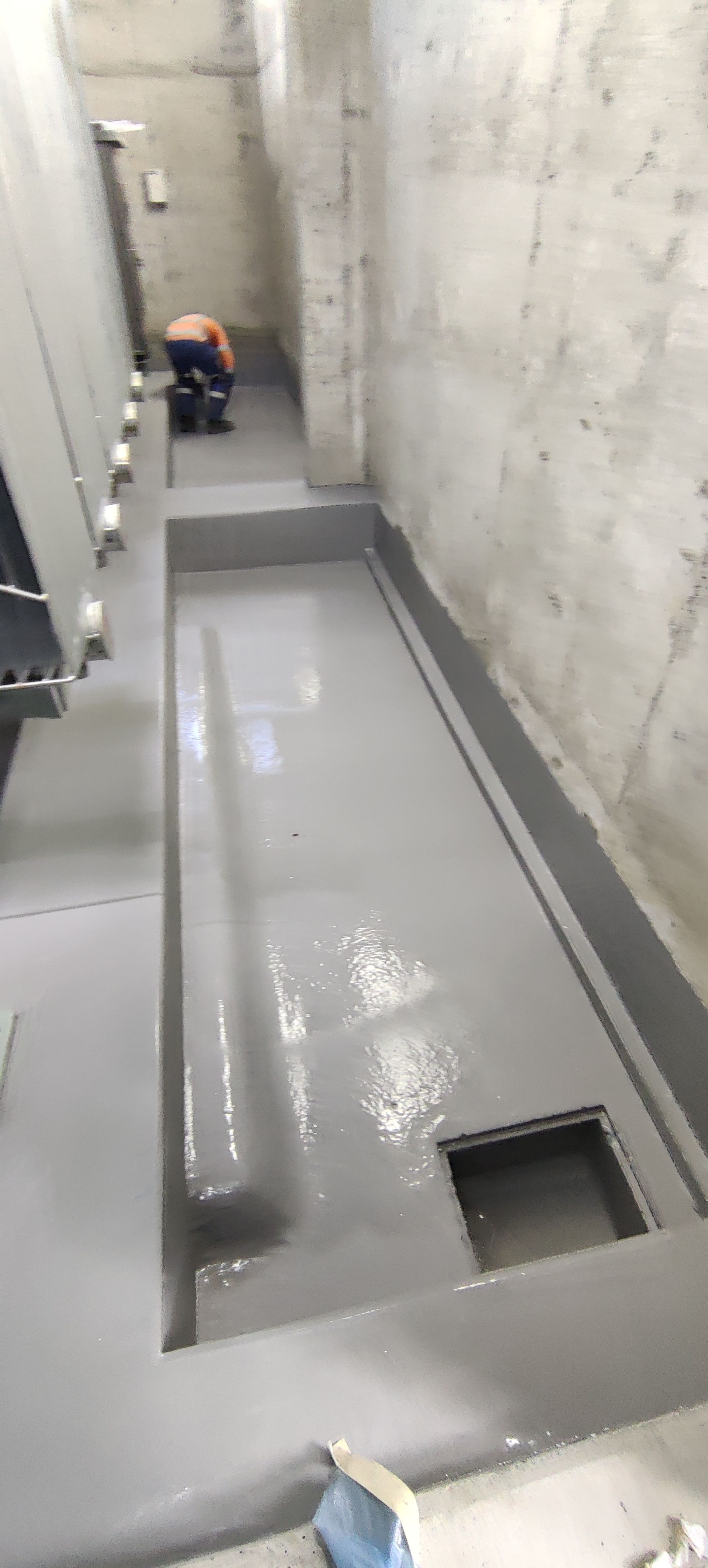 A person is painting a concrete floor in a room.