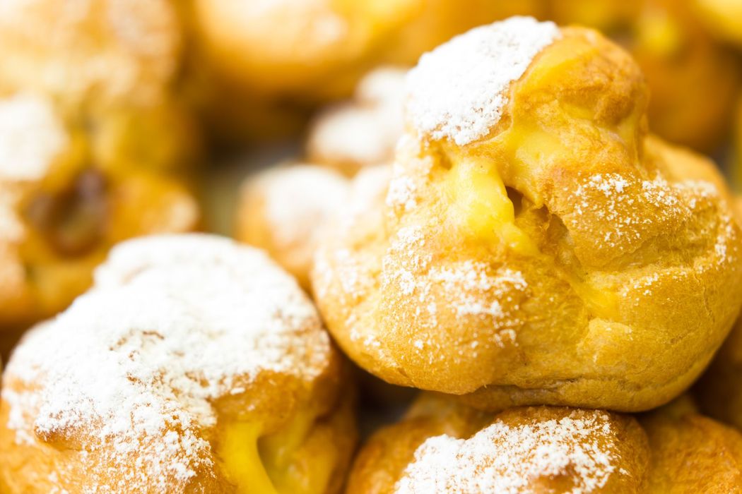 Bignè in polvere con dorate sfoglie di pasta choux, impilati strettamente l’uno accanto all’altro