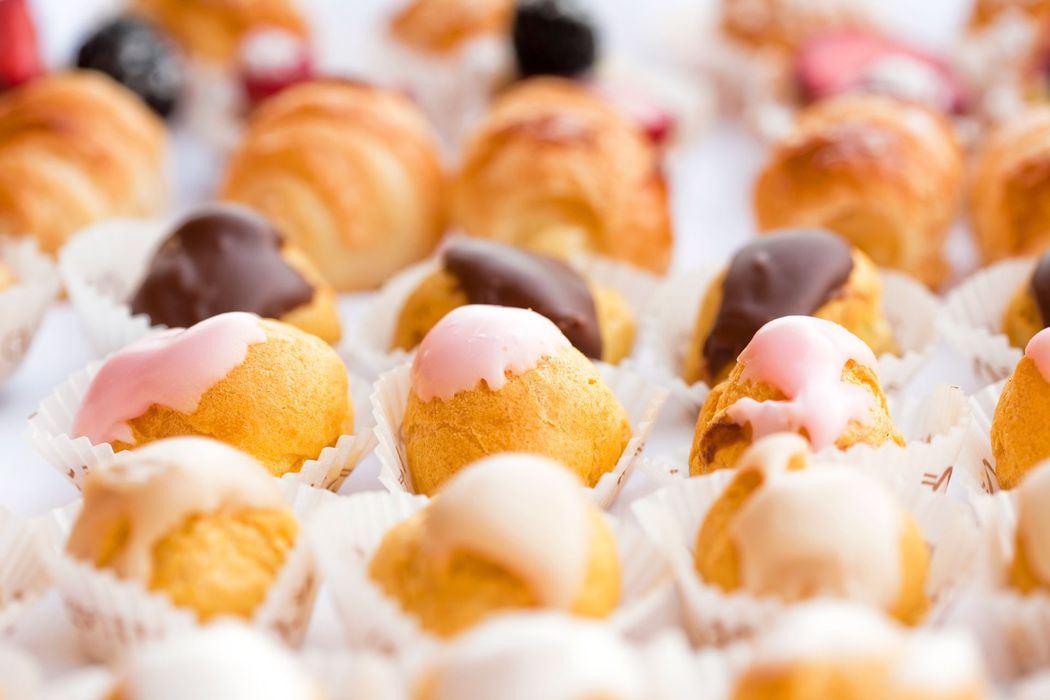 Ciambelle glassate assortite su un vassoio, con glasse rosa e al cioccolato, ricoperte di cocco grattugiato
