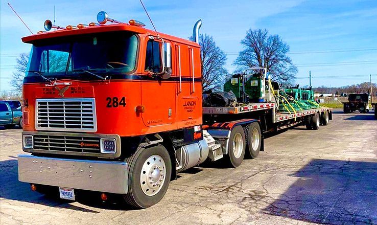 An orange semi-truck with the number 284 on the side is parked in a parking lot