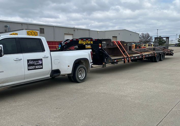 A white truck is towing a trailer in a parking lot