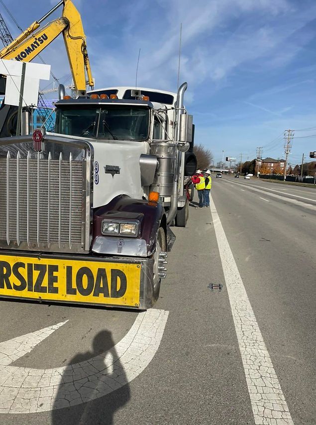 A truck is parked on the side of the road with a large yellow sign that says rsize load