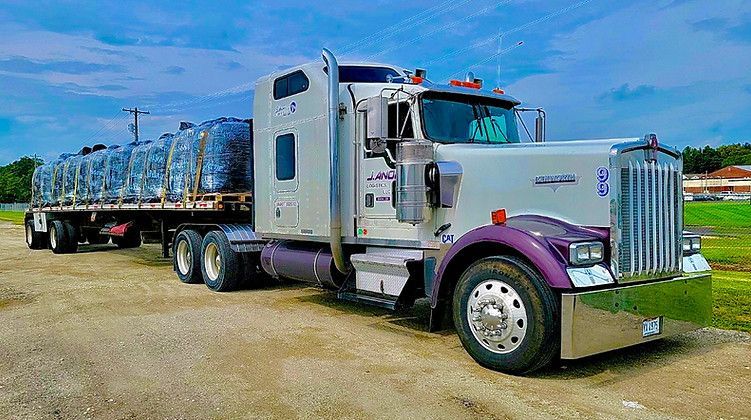 A semi-truck is parked on the side of a dirt road