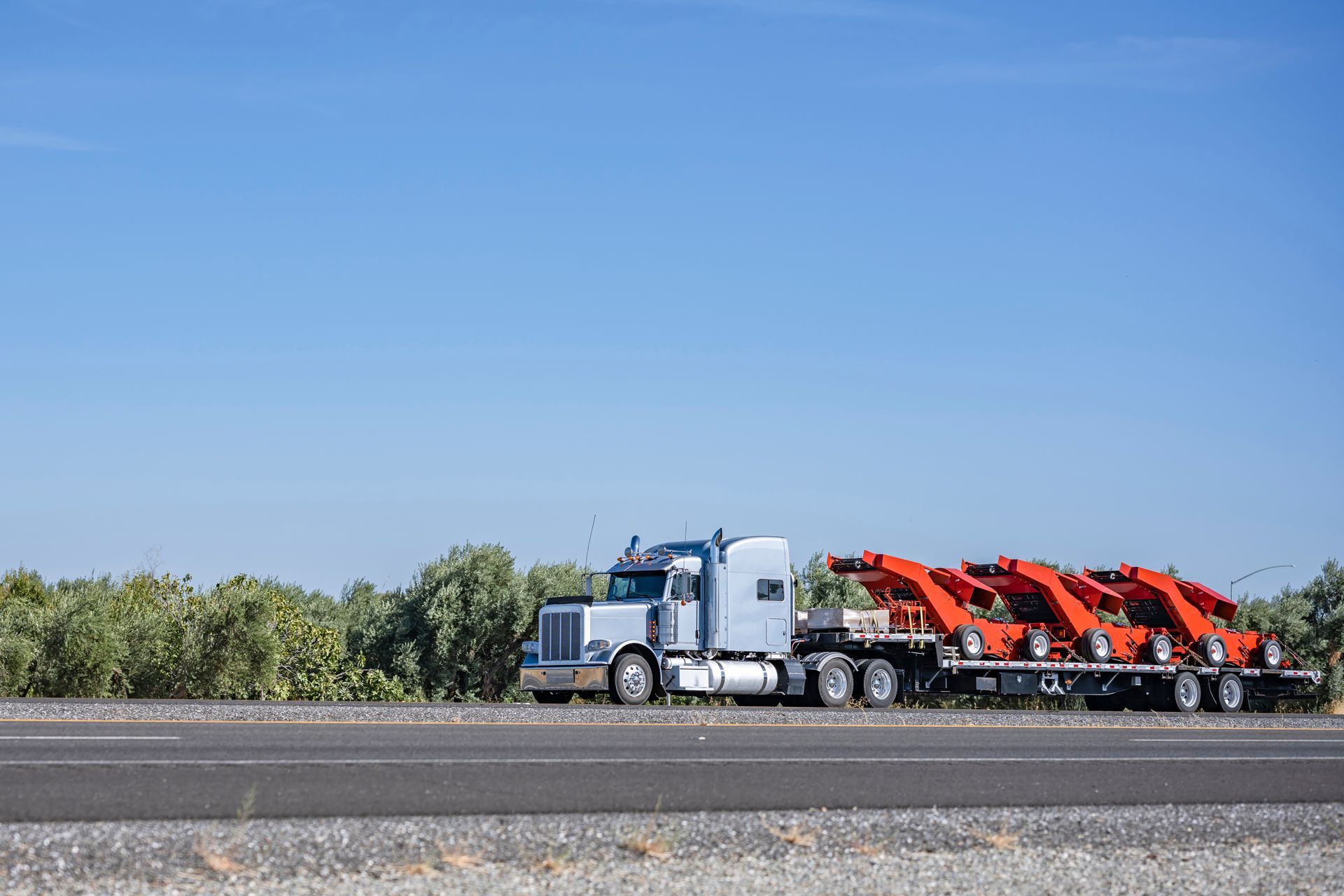 A semi truck is driving down a highway with a trailer full of cars.
