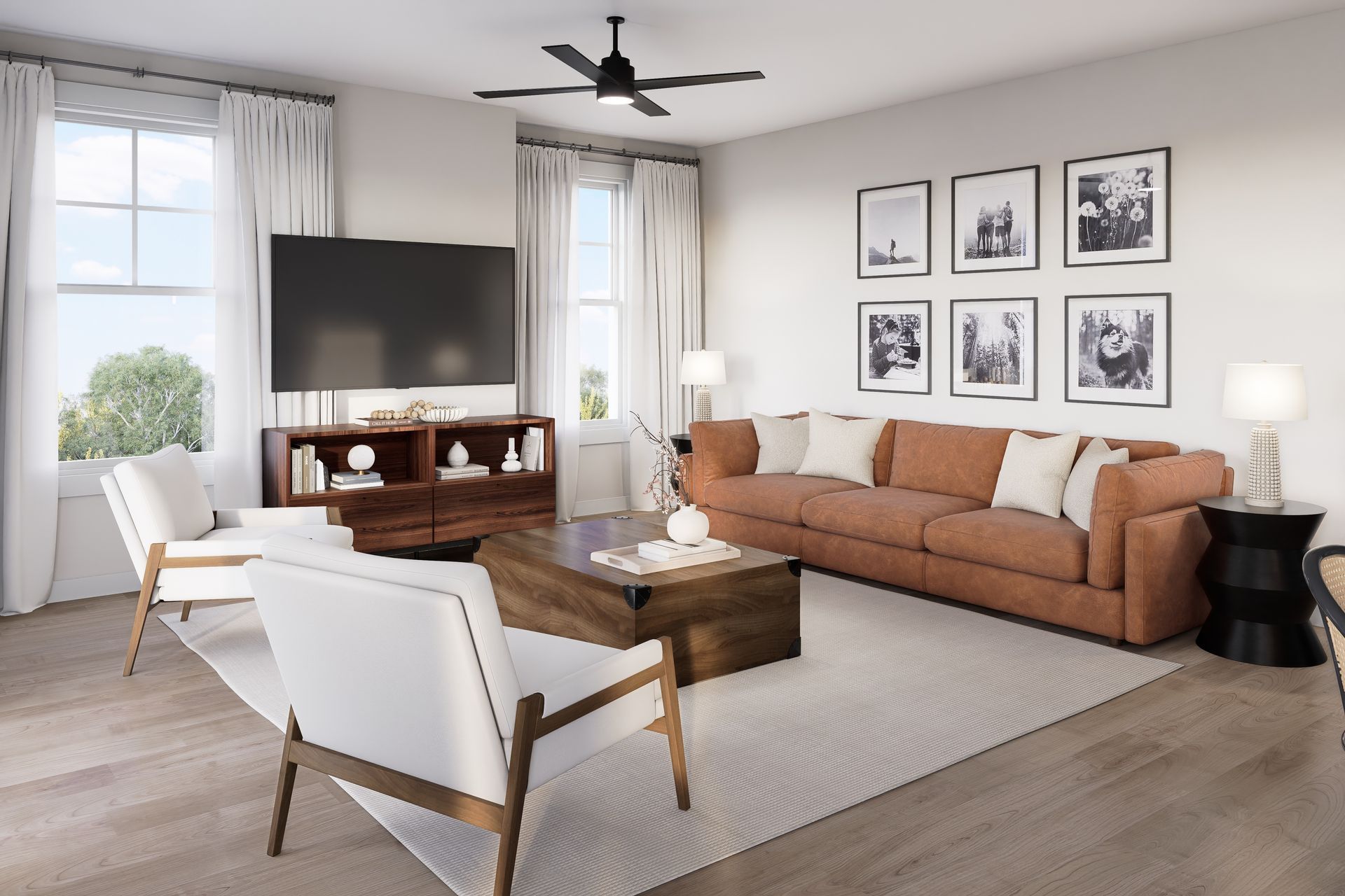 Bright living room with tan sofa, white chairs, wooden coffee table, TV, and framed wall art