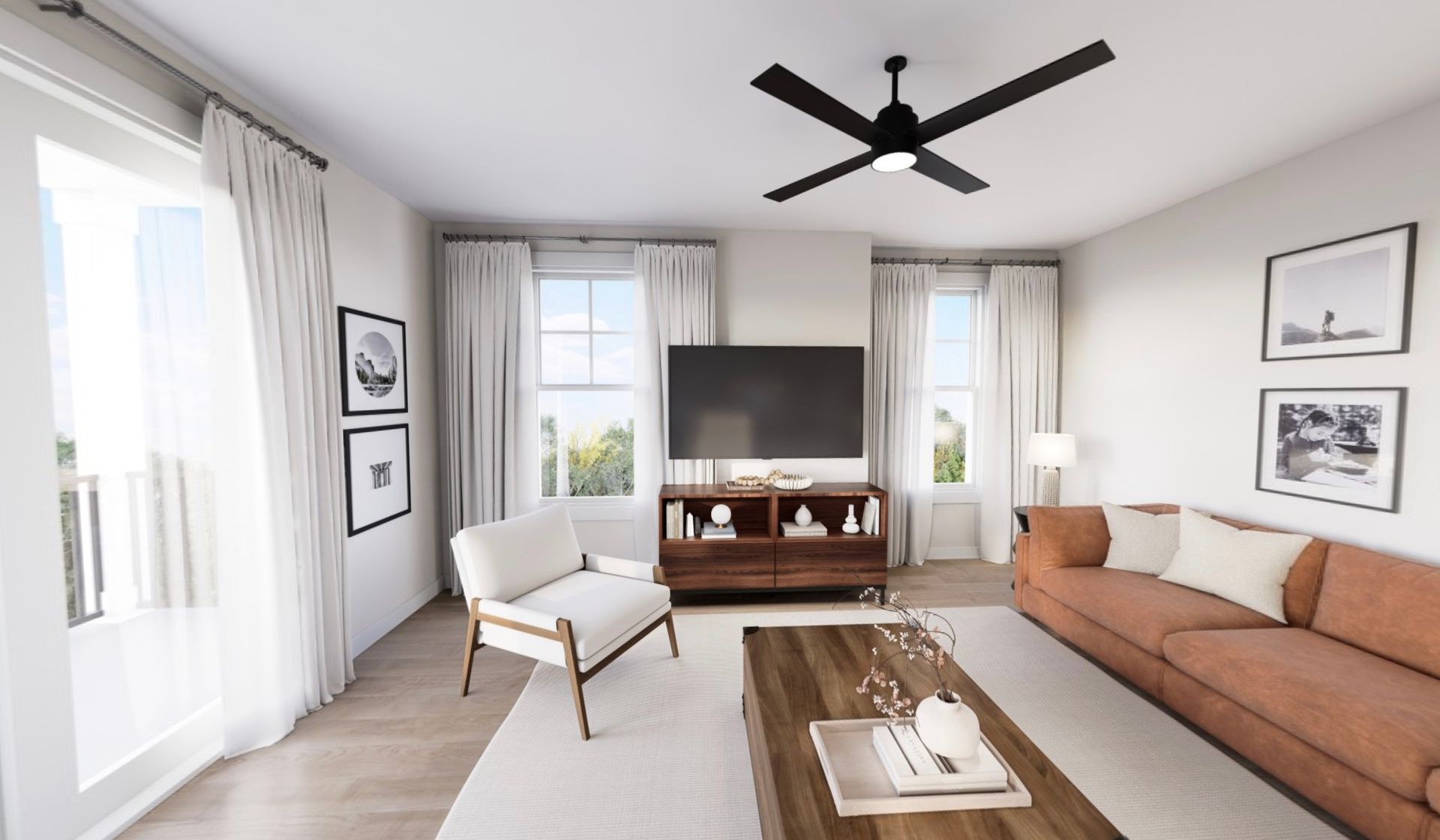 Bright living room with white walls, tan sofa, armchair, TV, coffee table, and large windows.