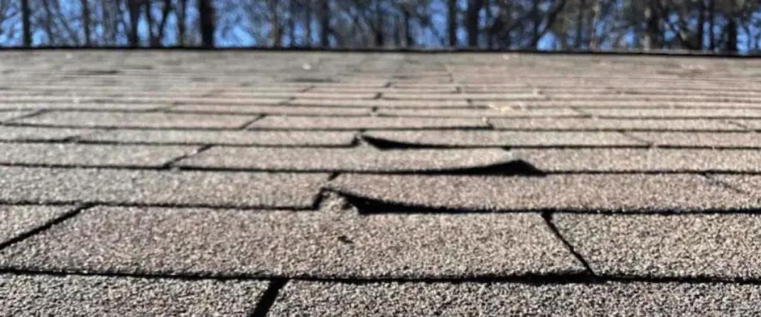 Close-up of gray and reddish-brown roof shingles with a diagonal seam.