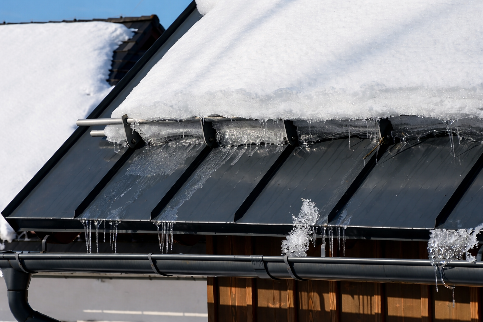 Rooftop with brown shingles and two white chimneys under a blue sky