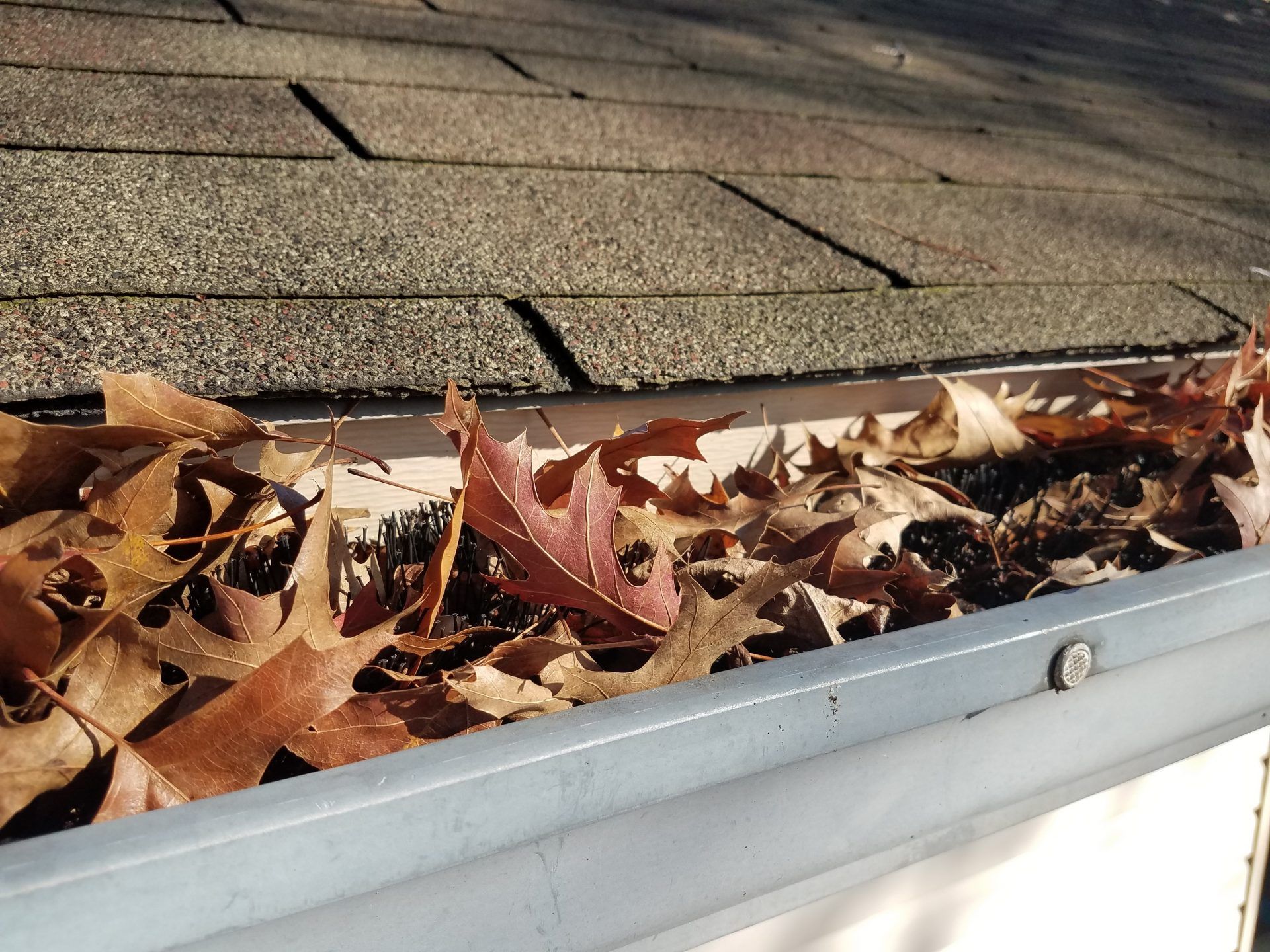 Red clay tile roof with a damaged, misaligned section under a partly cloudy sky
