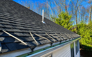 Worker installing black roofing felt on a flat roof with a torch applicator.