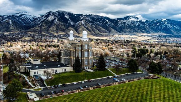 Aerial view of a downtown city with colorful buildings, a church, and mountains in the distance under a blue sky