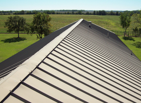 Close-up of a gray metal roof with standing seam panels and diagonal ridge lines