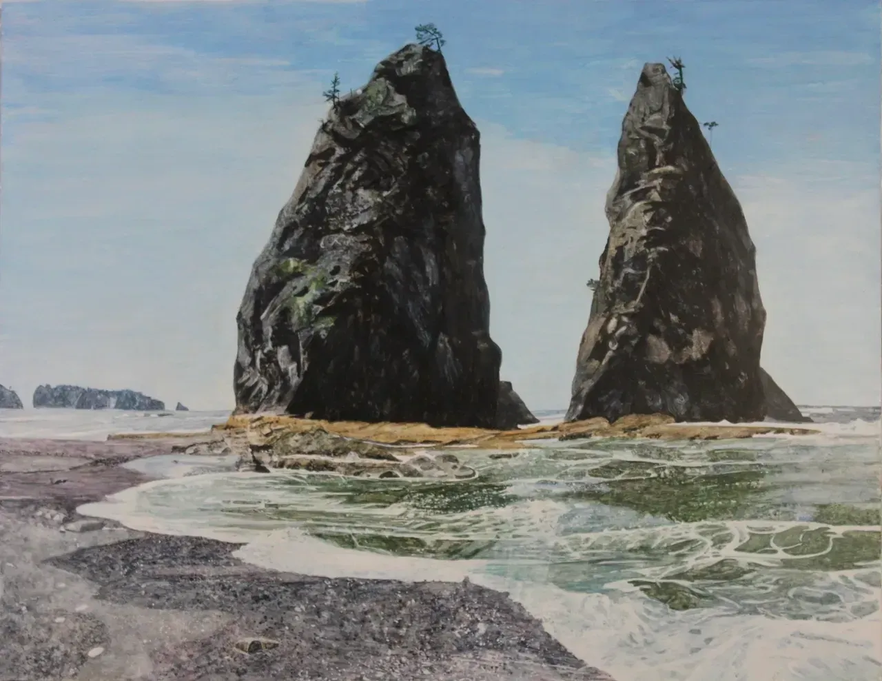 Two tall sea stacks rise from a rocky shore beside surf under a pale blue sky.