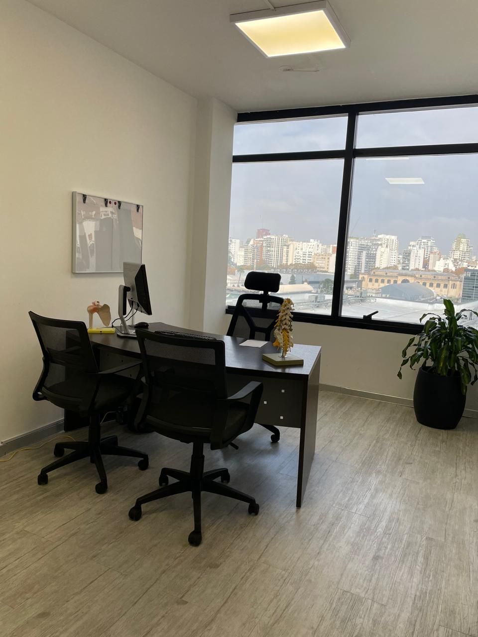 Una habitación con un escritorio y sillas y una ventana grande.