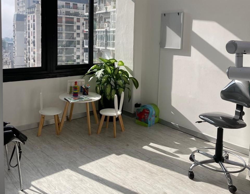Una habitación con una mesa y sillas frente a una ventana.