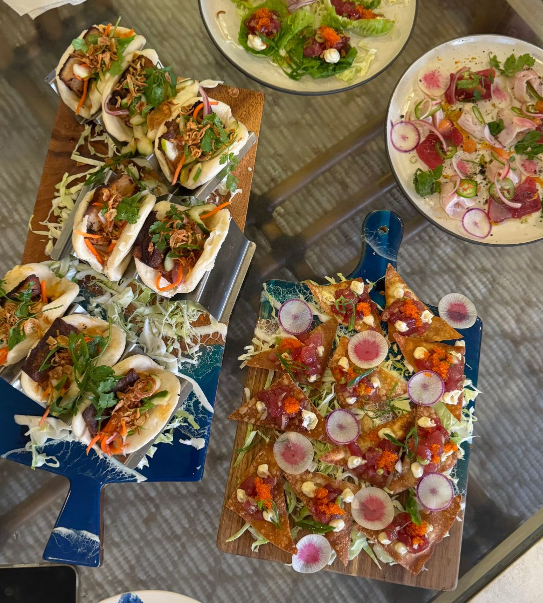 Assorted plated tacos and garnished dishes on a table, with colorful vegetables and sauces.