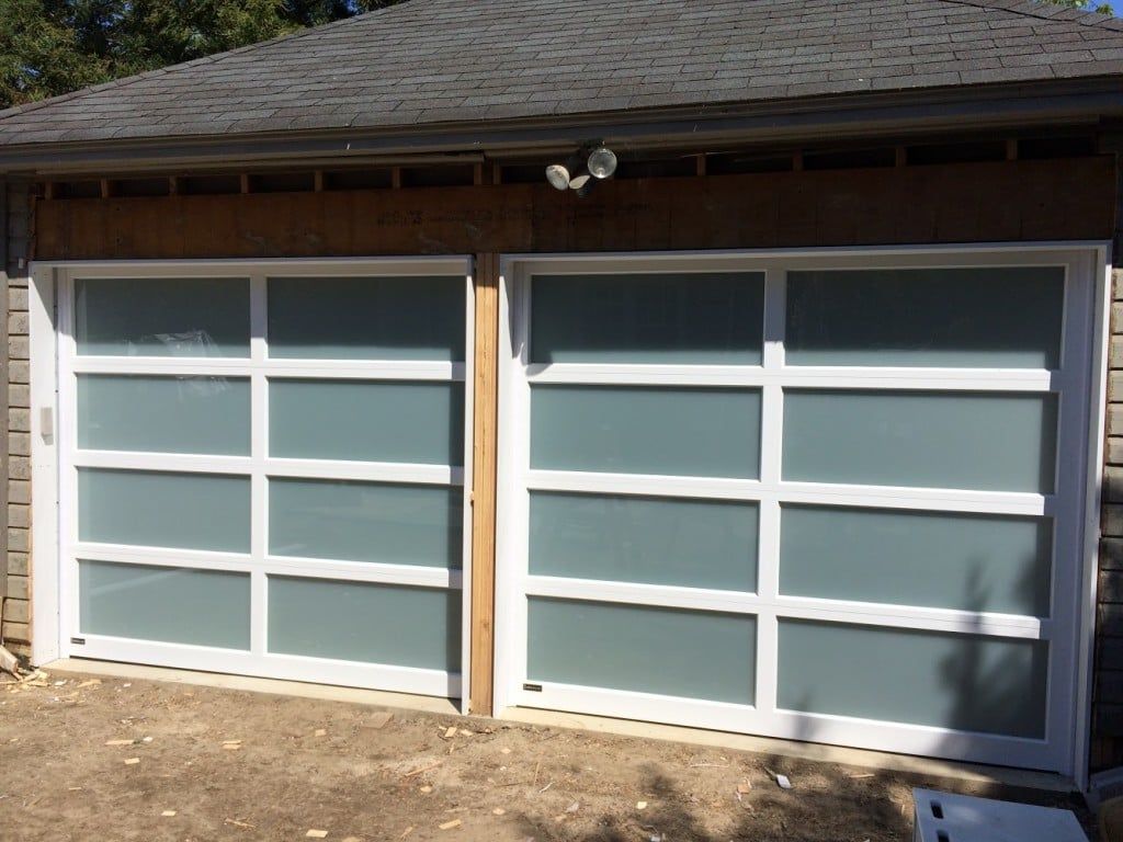 Two gray garage doors with white trim on a house exterior