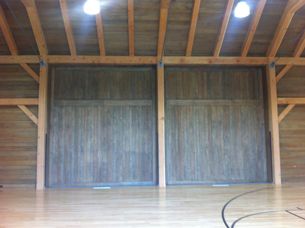Empty indoor wooden stage with overhead lights and large sliding doors in the background