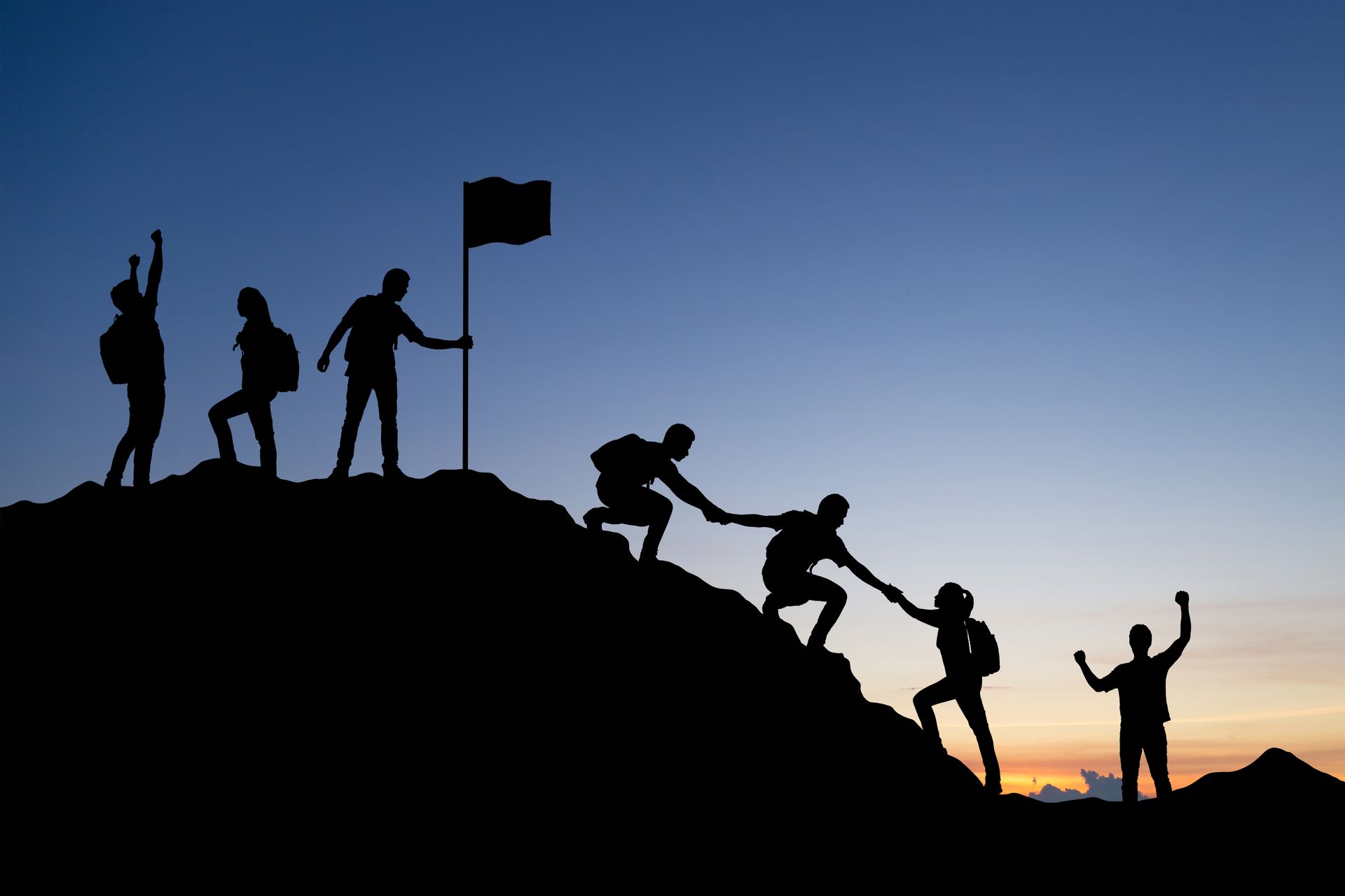 Leader helping team up a mountain.
