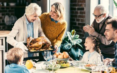 A family is sitting at a table eating a turkey.