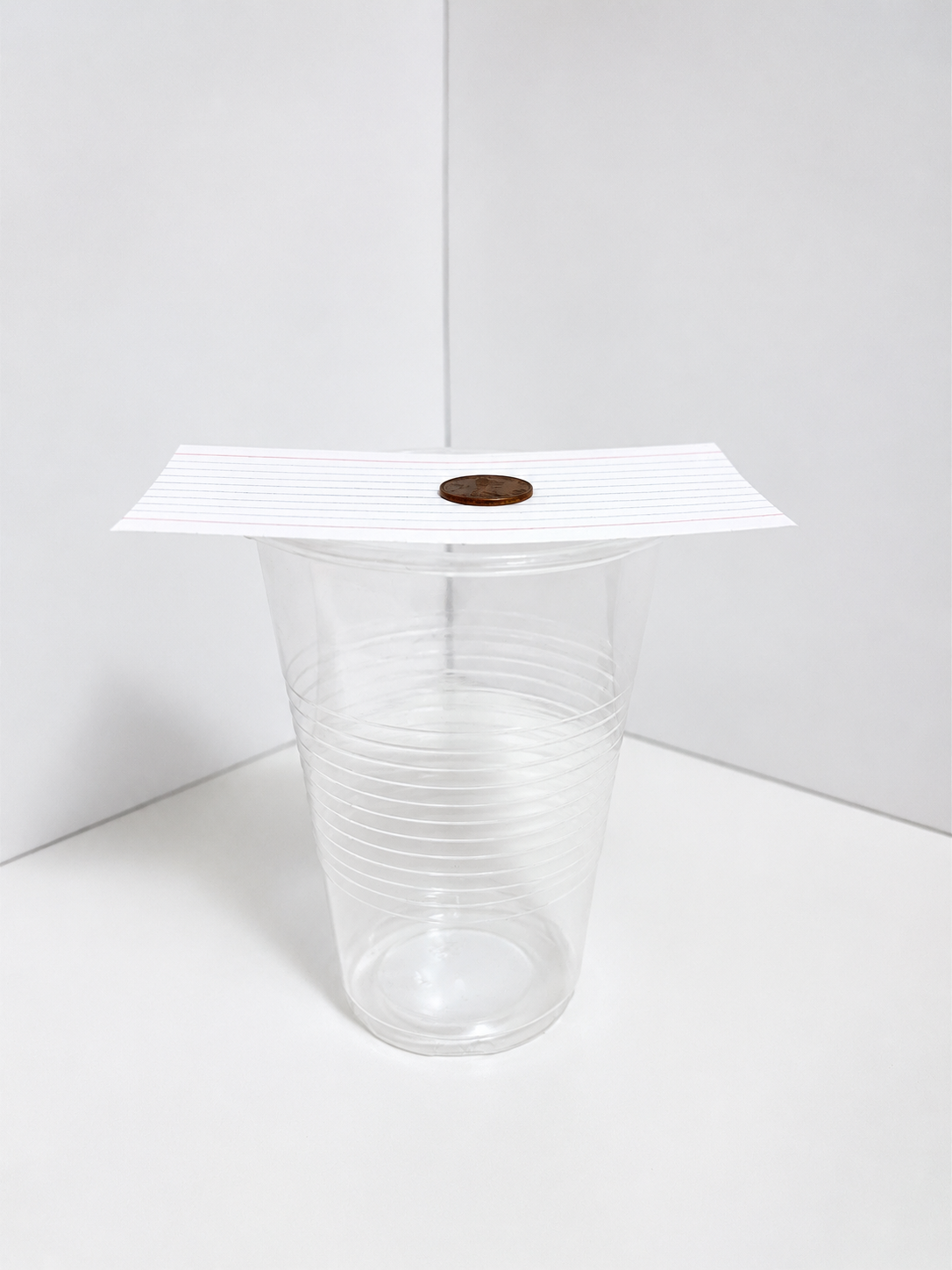 Coin resting on an index card over a plastic cup for a hands-on Newton's First Law of Motion