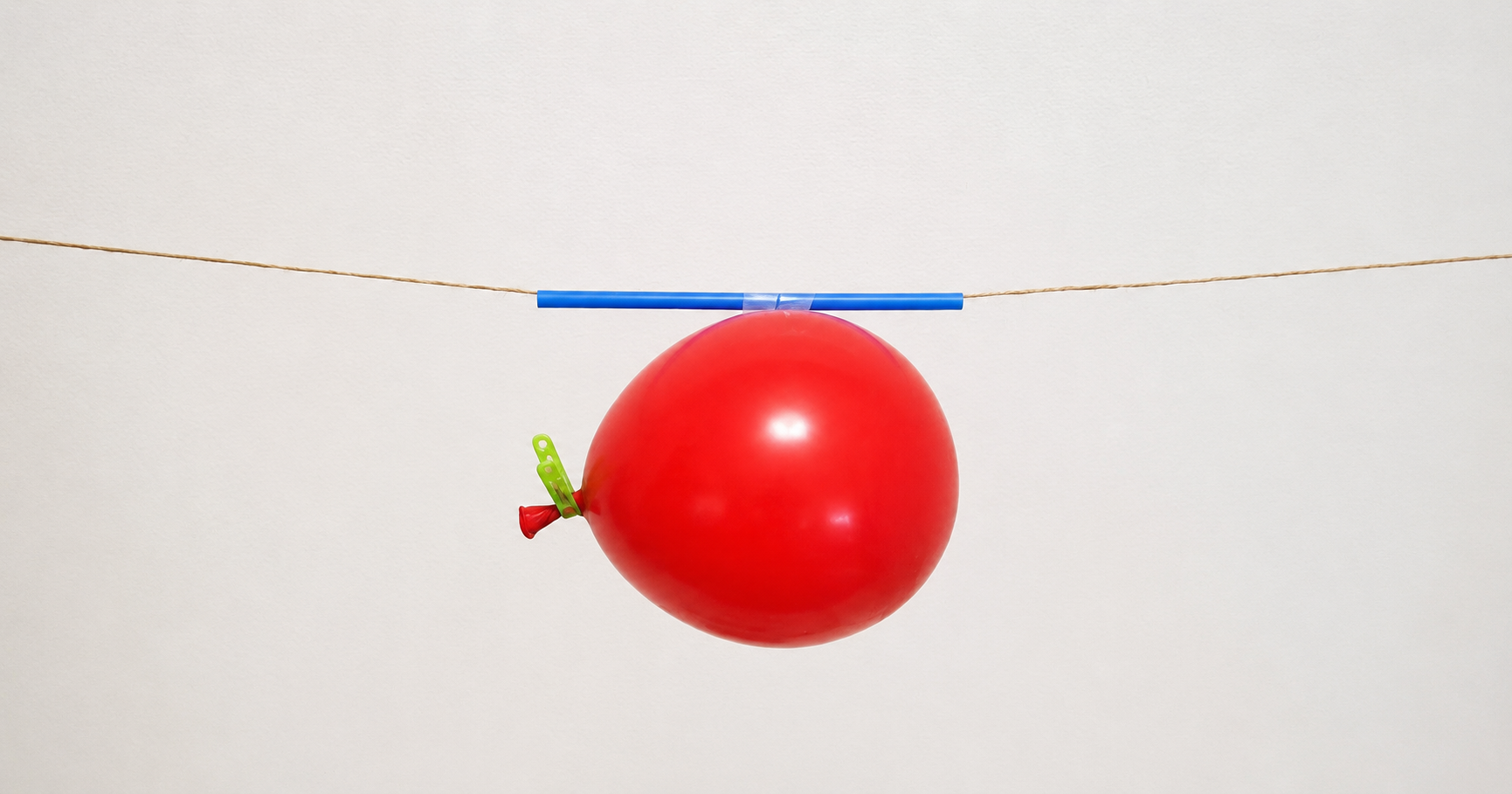 Balloon rocket science experiment demonstrating force and motion with a balloon attached to a straw on a string.