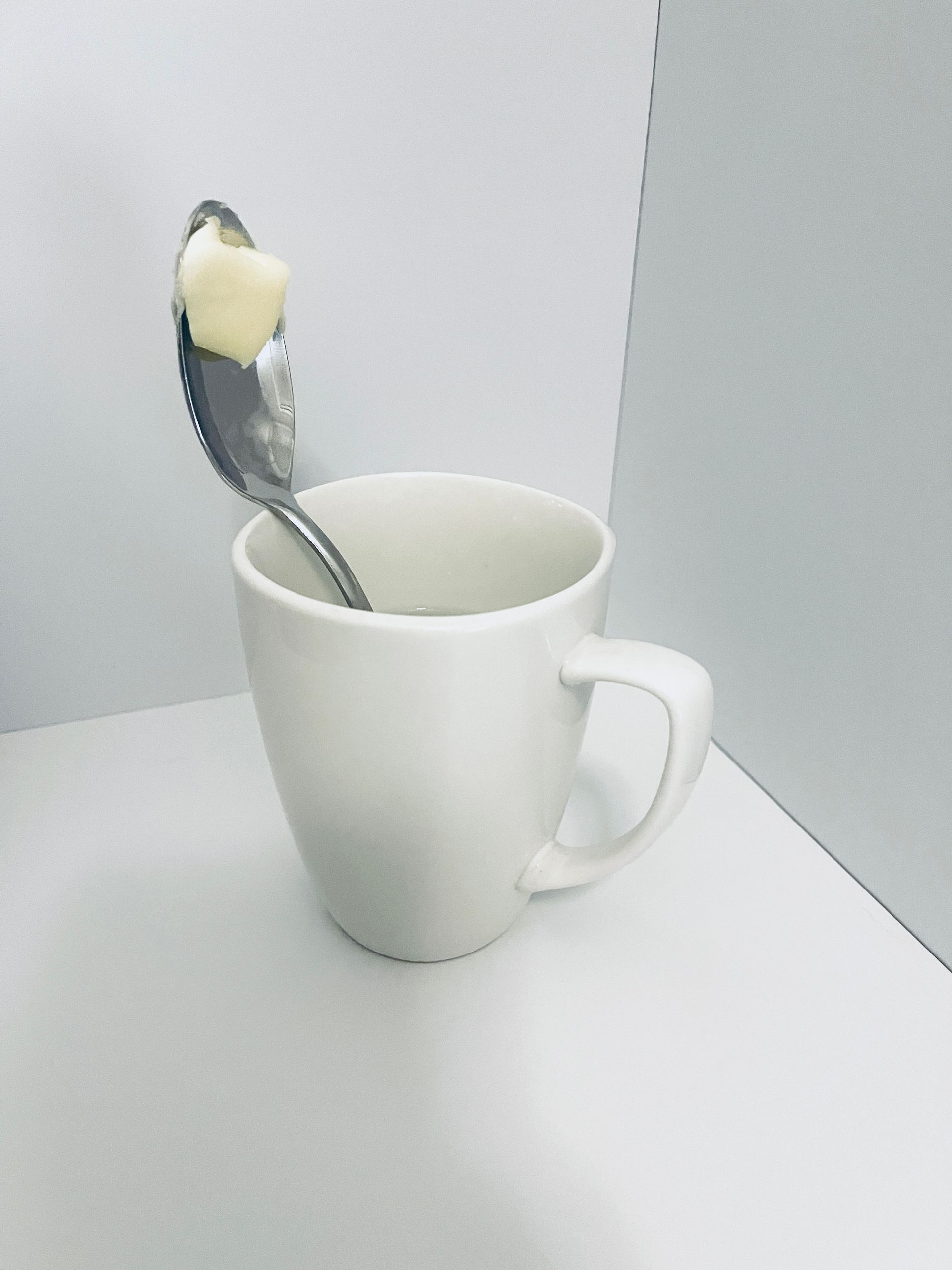 Coffee mug with a metal spoon and butter on it.