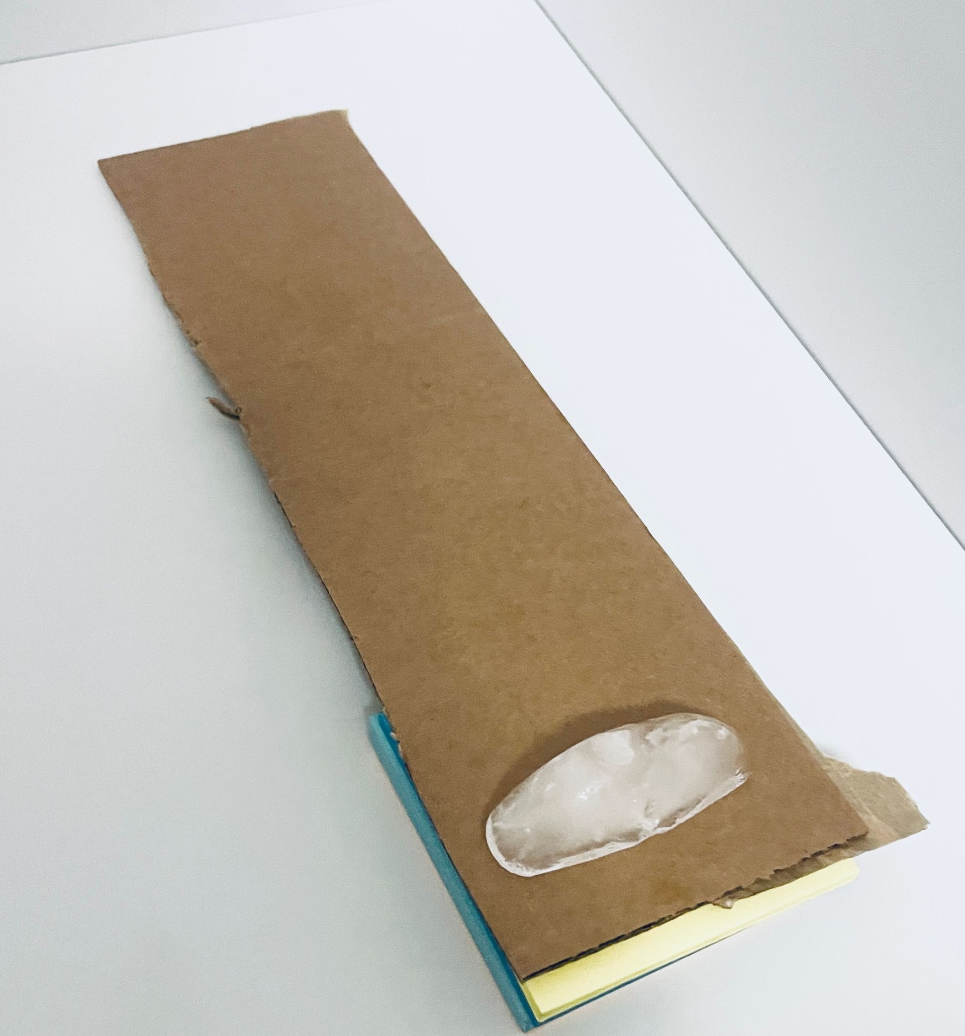 Cardboard ramp with an ice cube on it.