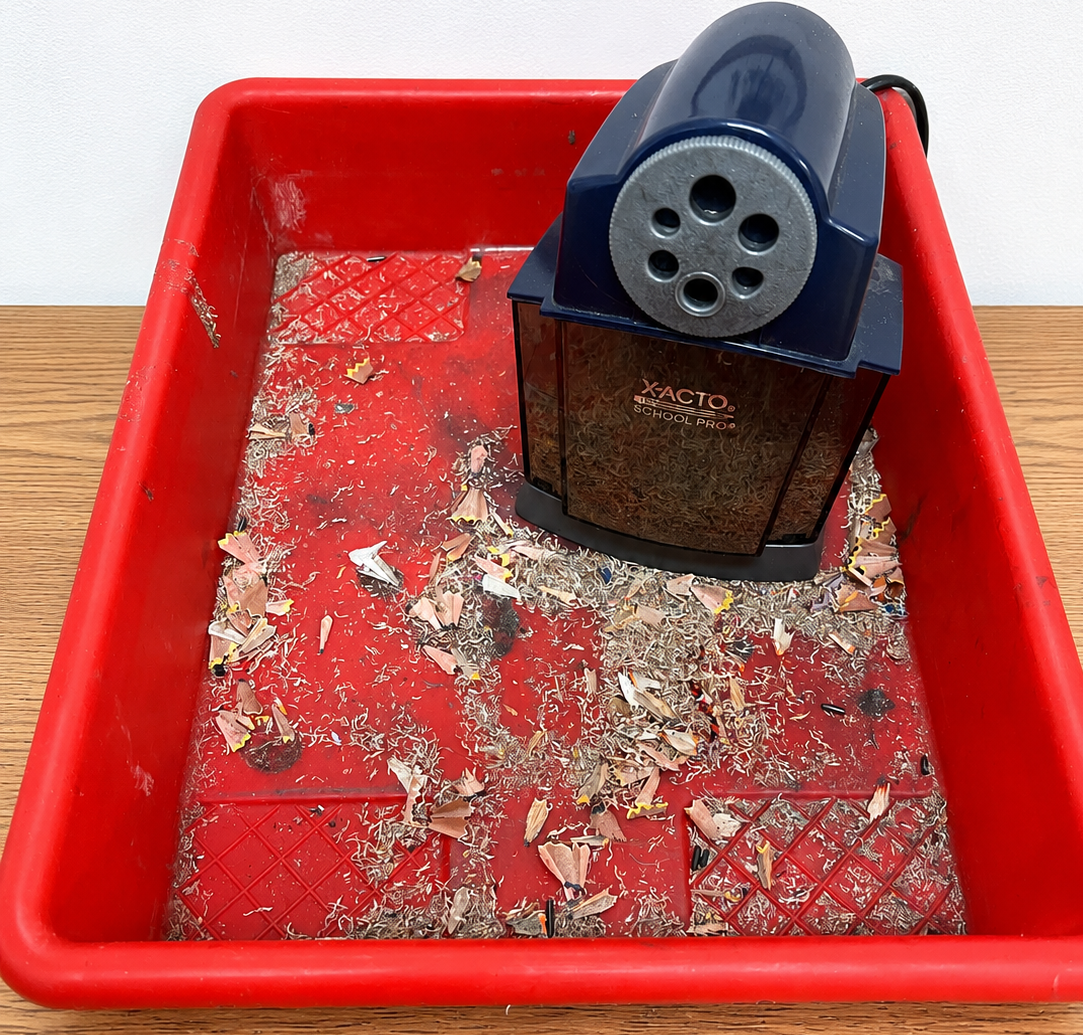 Picture of a pencil sharpener sitting inside a bin.