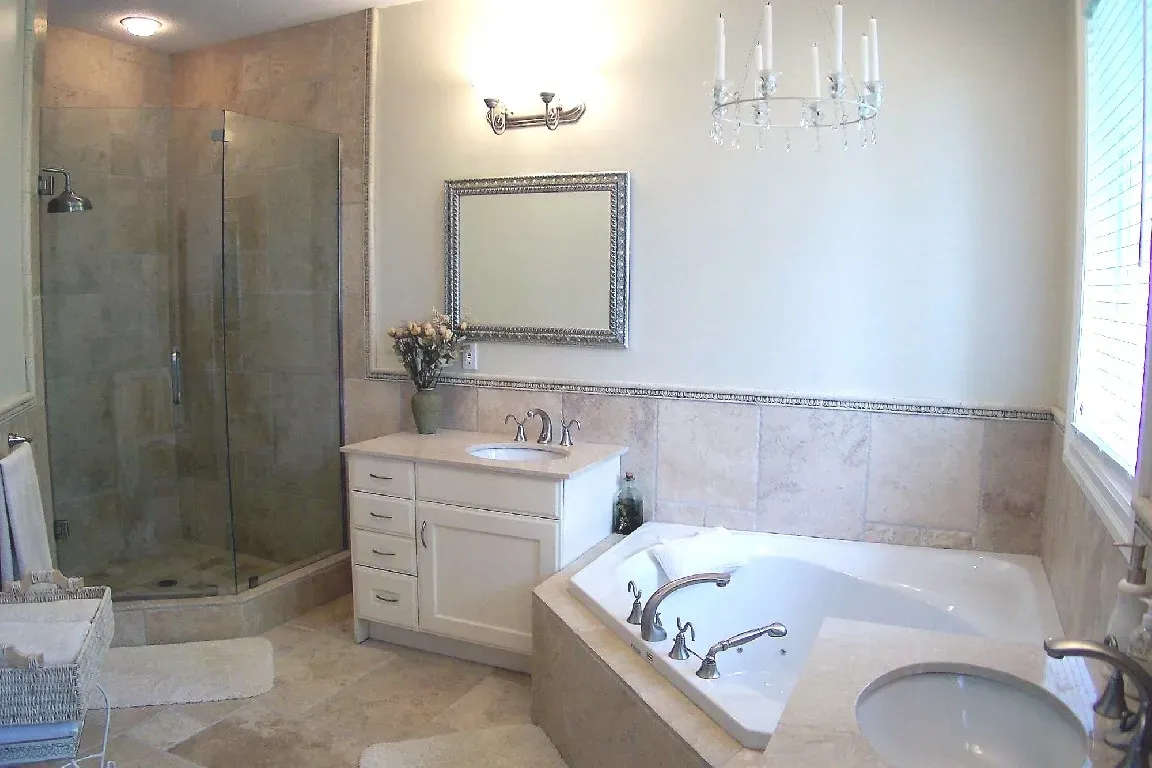 A neutral-toned bathroom with a glass shower, a white vanity with a mirror, and a built-in jetted bathtub.