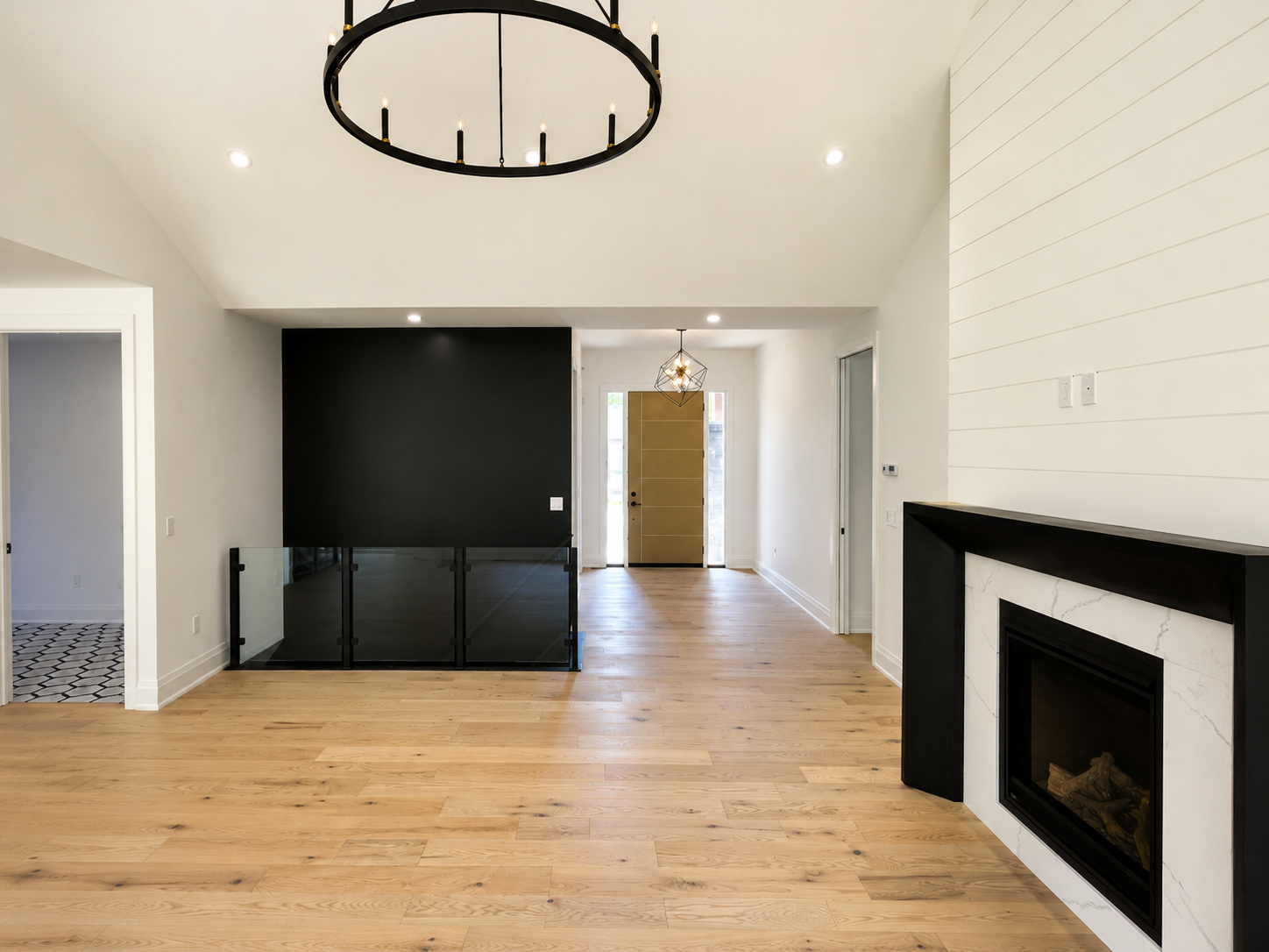 Modern living room with wood floors, black fireplace, and black built-in shelving against white walls