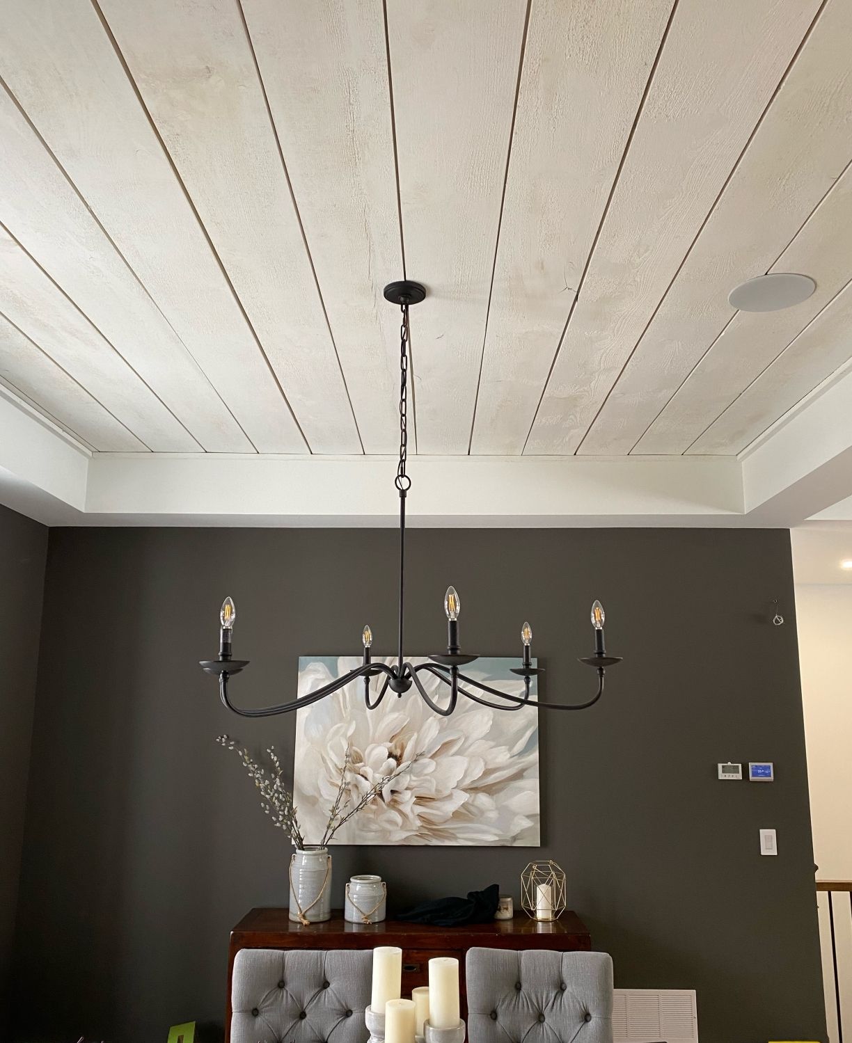 Dining room with black chandelier, floral wall art, dark gray walls, and a tray ceiling.