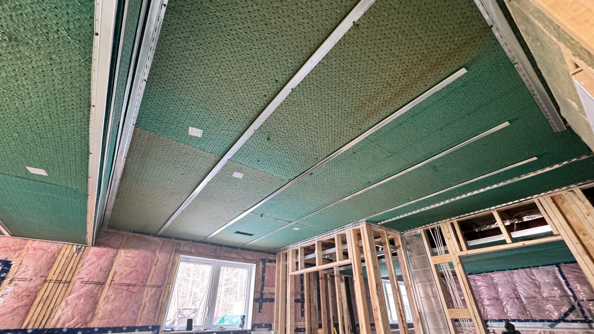 Partially built room with green drywall ceiling panels and exposed wooden framing