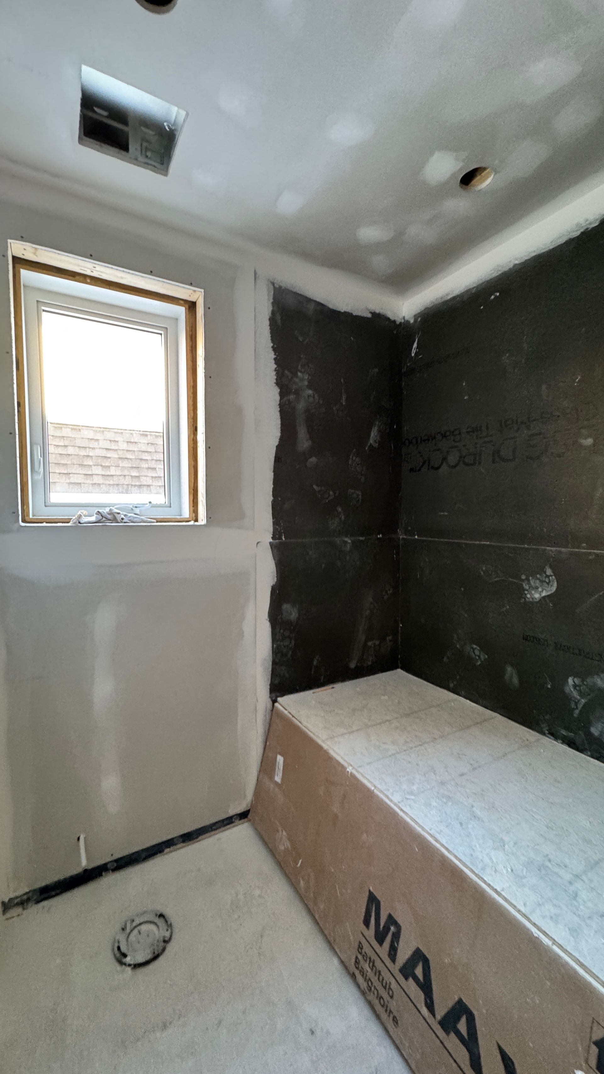 Partially renovated bathroom with unfinished walls, a small window, and a bathtub under construction