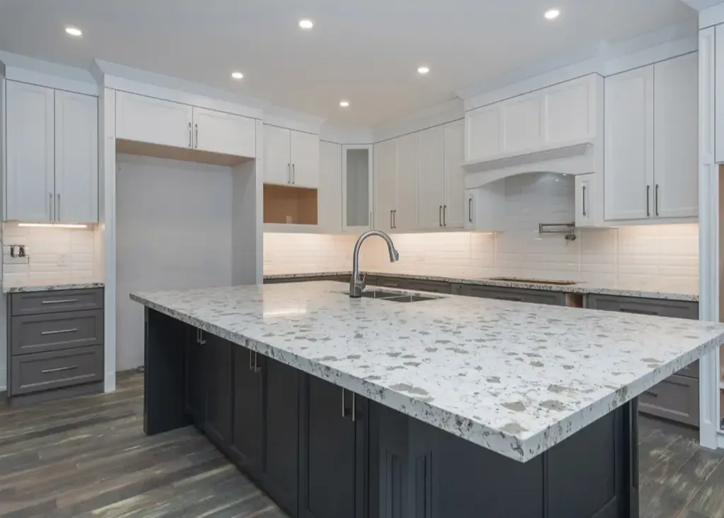 Modern kitchen with a white-topped island, dark lower cabinets, white upper cabinets, and light gray wood-look flooring.