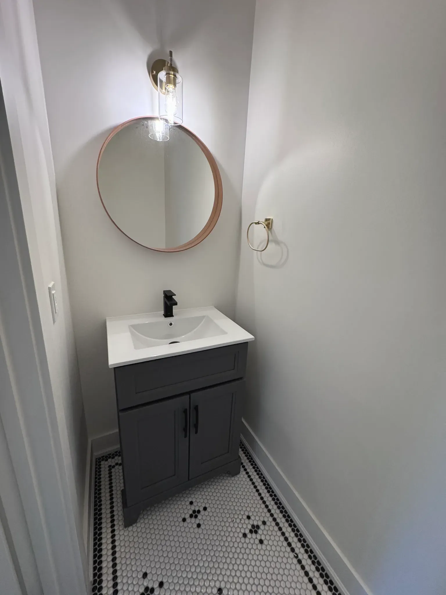 powder room with white penny tile and black border