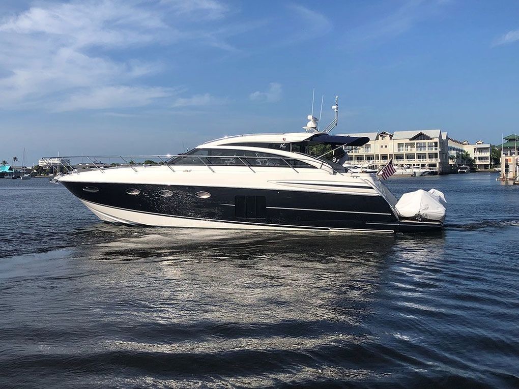 A sleek, white and dark blue motor yacht cruising on blue water under a bright sky.